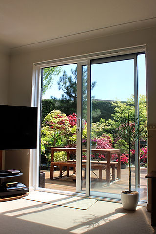 Sunlit room with glass sliding doors opening to a lush garden