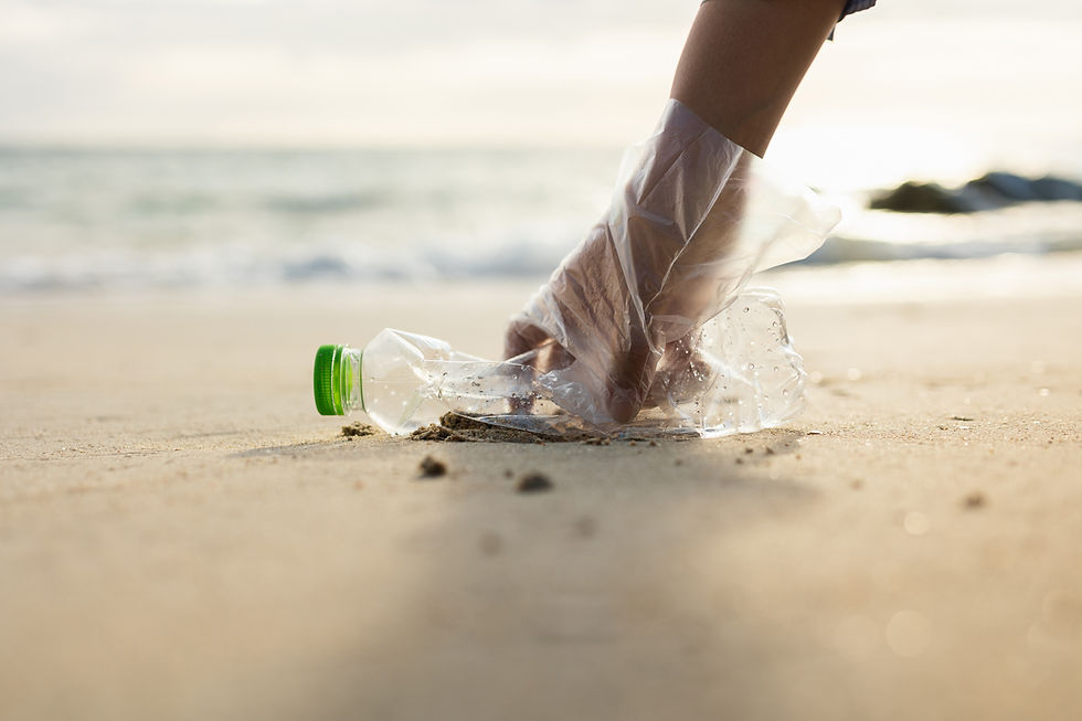 Hand picking up plastic bottle from sand