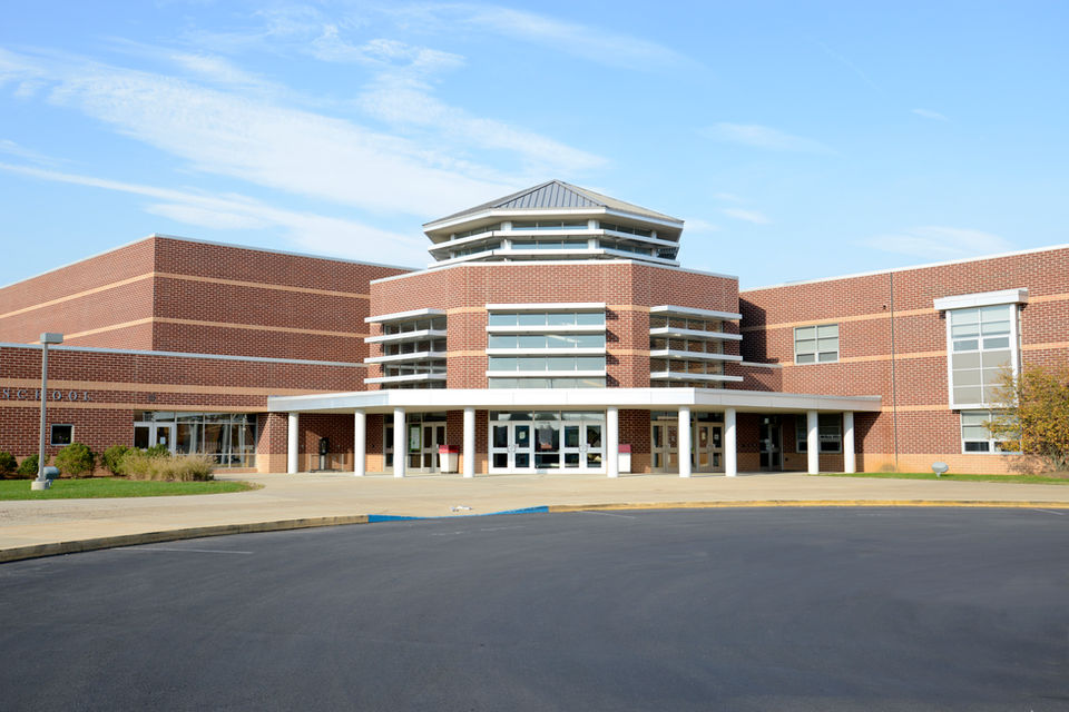 Exterior view of a large brick school building, blue sky background.