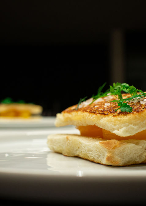 Golden seared bread with yellow filling and fresh herbs.