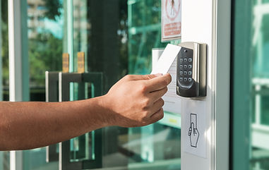 An outstretched arm holding a key card of to a card reader.