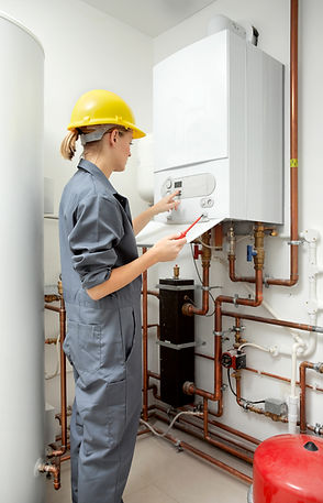 Female gas engineer in overalls inspecting residential boiler pipework and setup