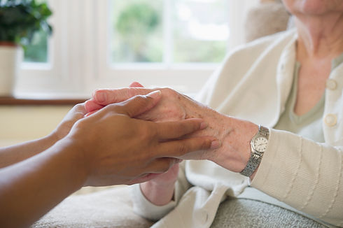 Close up of a younger hand gently holding an elderly person's hand to show care and reassurance