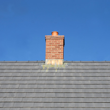 Gray tile roof and chimney on house with blue sky background
