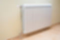 White modern radiator on a wall with a wooden floor