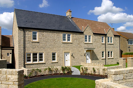 Charming stone cottage with two white doors, small windows, and a black roof 