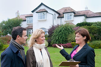 Mid adult couple and female estate agent outside house