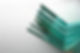 Stacked glass sheets with green-tinted edges on a white surface