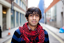 South Asian man with red scarf posing in the middle of a street