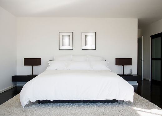Modern minimalist bedroom with double bed white bedding dark bedside lamps