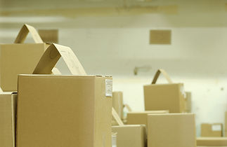 A stack of brown cardboard boxes with labels and flaps showing