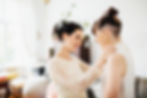 Brides getting ready for wedding, both wearing wedding gowns