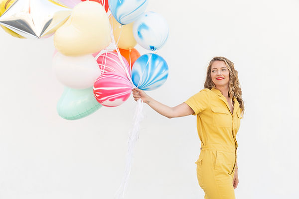 Glückliche Frau hält Luftballons und blickt erleichtert, nachdem sie ihre Höhenangst mit Hypnotherapie in Frankfurt überwunden hat