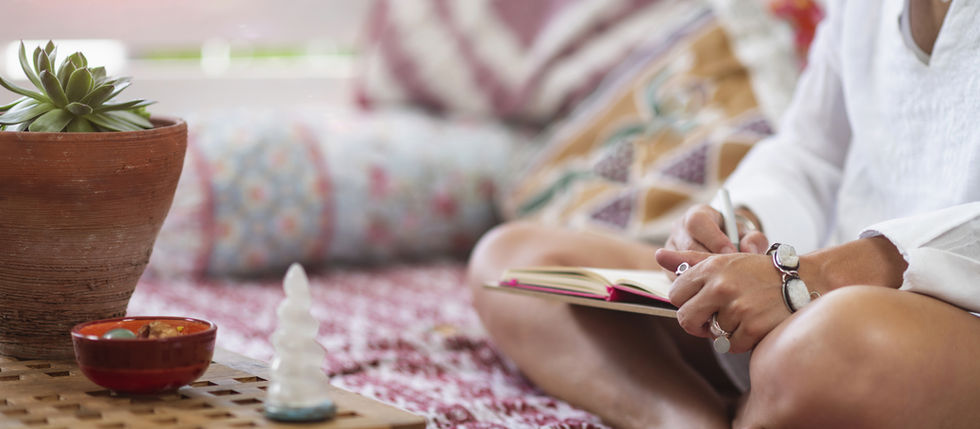 Woman sitting on the floor, writing in a book. Cosy background.