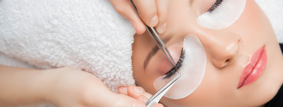 Künstliche wimper wimpernsextensions wird mit einer pintette auf die echte wimper geklebt