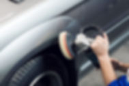 A person polishes a silver car with an electric buffer