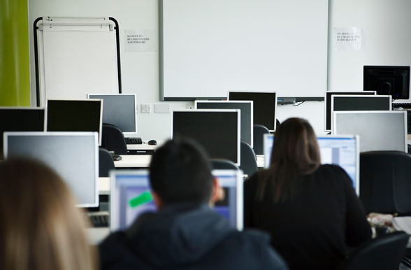 Computer room with focus on white board and flipchart. Multiracial group of students