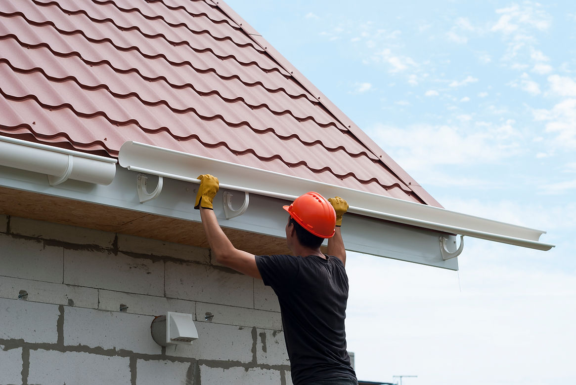 Worker installs the gutter system on the roof