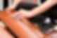 A person's hands placing a new reddish-brown terracotta tile on a roof