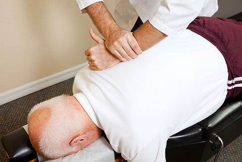 Closeup of chiropractors hands doing spinal adjustment on senior man