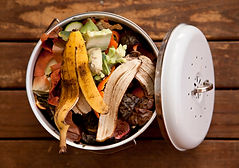 Overhead view of fruit and vegetable scraps in a white enamel container, ready to go in th