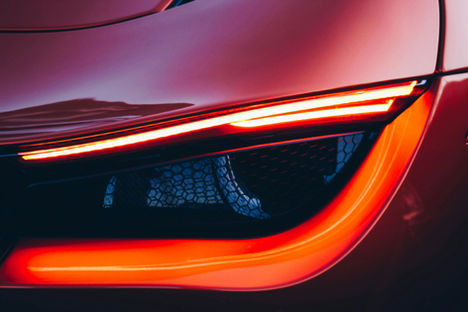 Red car headlight detail with illuminated LED lights, carbon fiber accents close up