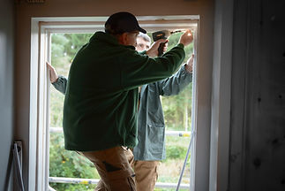 Father and son builders installing new window in house