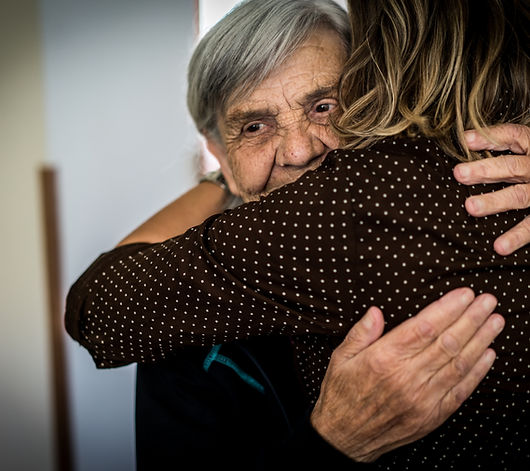 A senior individual receiving a comforting hug from a caregiver or family member, conveying warmth and support.