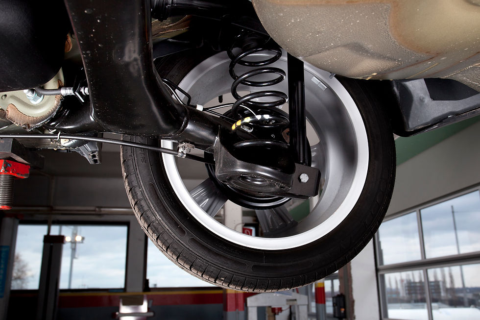 Underside view of a car showing a wheel assembly with the coil spring and shock absorber suspension system