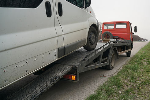 Side view of a white van loaded onto a breakdown recovery truck flatbed ready for transport