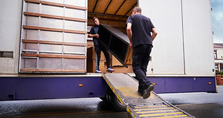 two persons lifting furniture into a truck