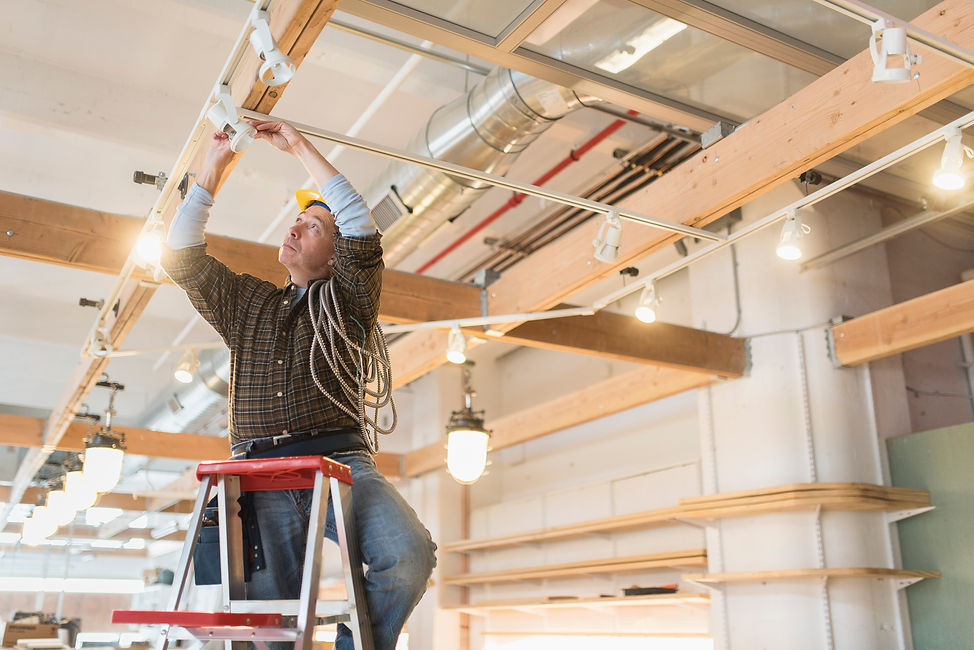An electrician installing the ceiling lights at a commercial space