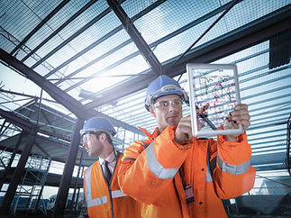 worker inspects a tablet displaying blueprints