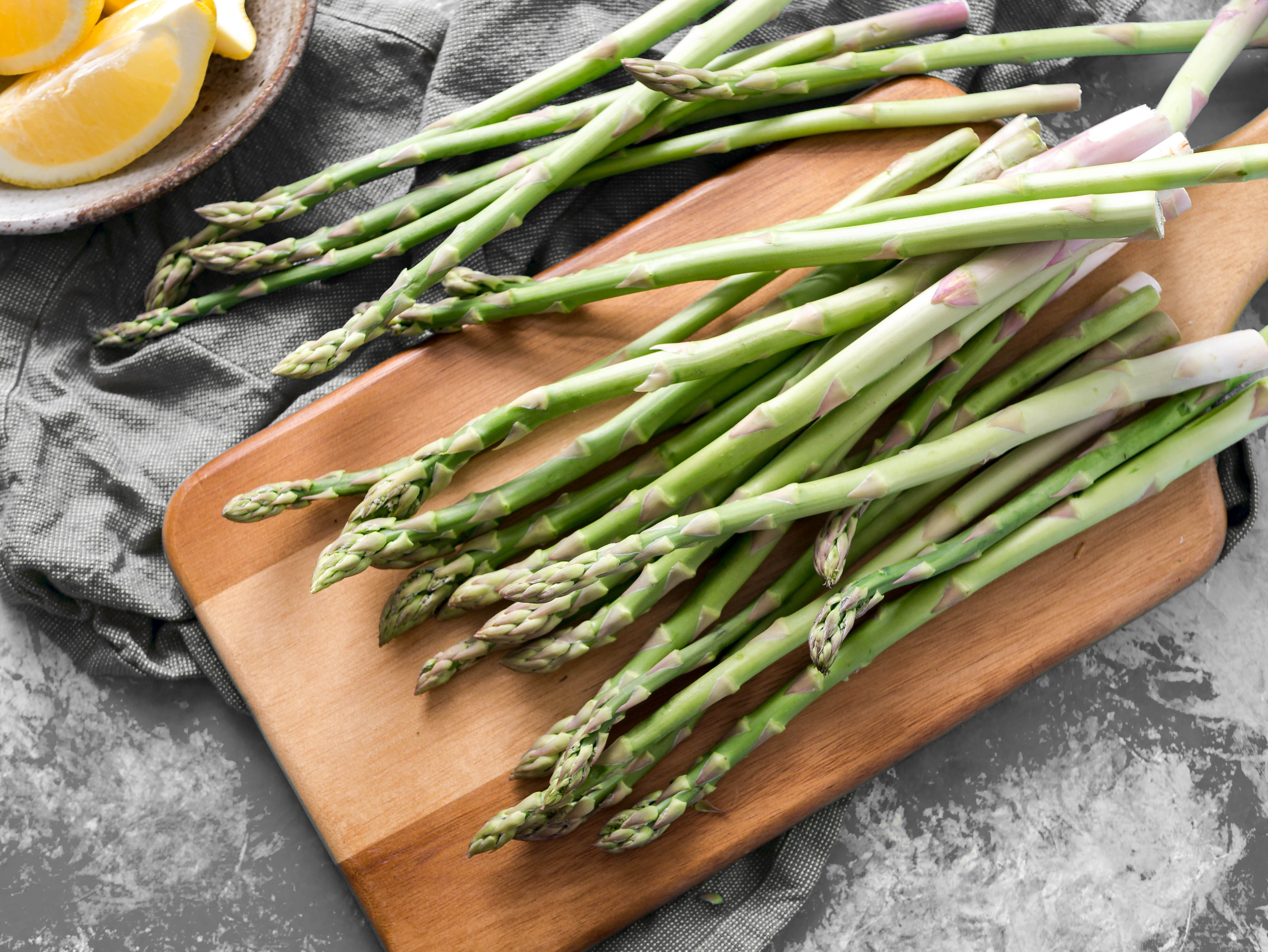 A loose bundle of asparagus set on a wooden cutting board