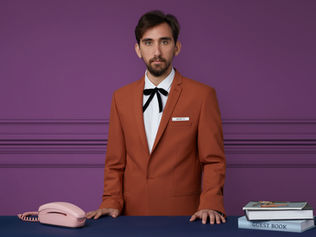 Man in red coat pretending to be a hotel concierge. 