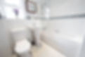 A general view of a bathroom with white suite and glass shower screen