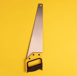 A hand saw with a black handle and metallic blade is placed against a bright yellow background. There's no visible text.
