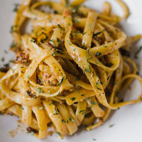 Golden fettuccine pasta garnished with fresh herbs, combined with sun-dried tomatoes and a light, flavorful sauce.