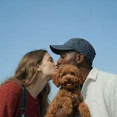 Couple kissing, man holding a small brown dog