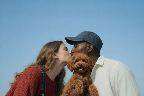 White-female-and-black-male-kissing-with-a-goldendoodle-smiling-in-front-of-them-outside-in-Orlando