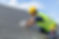 A worker repairs a roof shingle under a blue sky
