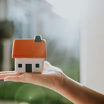 Hand holding a little house with an orange roof. Conceptual image with space for copy