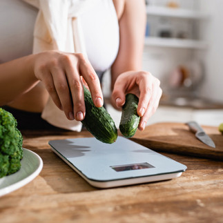 girl weighing cucumbers on a food scale 