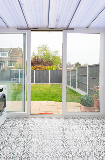 White uPVC patio sliding doors opening to green lawn and garden area