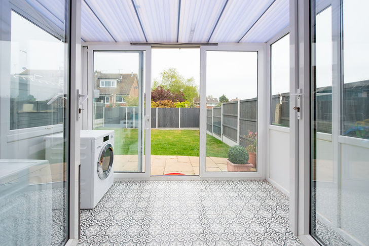 Bright sunroom with patterned tile flooring and glass sliding doors leading to a green backyard