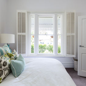 bedroom with white window shutters open
