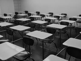 Sala de aula vazia com carteiras organizadas em fileiras. A imagem ilustra os desafios enfrentados pelos sistemas educacionais diante das transformações provocadas pela inteligência artificial e pela necessidade de desenvolver capacidades institucionais para sua implementação.