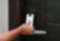 A hand holds a key card near a digital door lock, indicating contactless entry at a secure access point