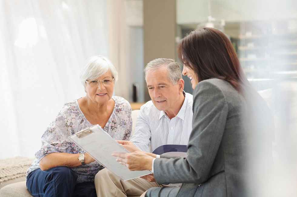 A professional showing registered legal documents on a clipboard to a senior couple on a sofa.