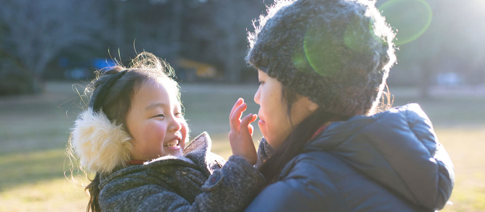 Mother holding a child. Child's fingers are touching mother's face. Child is smiling.